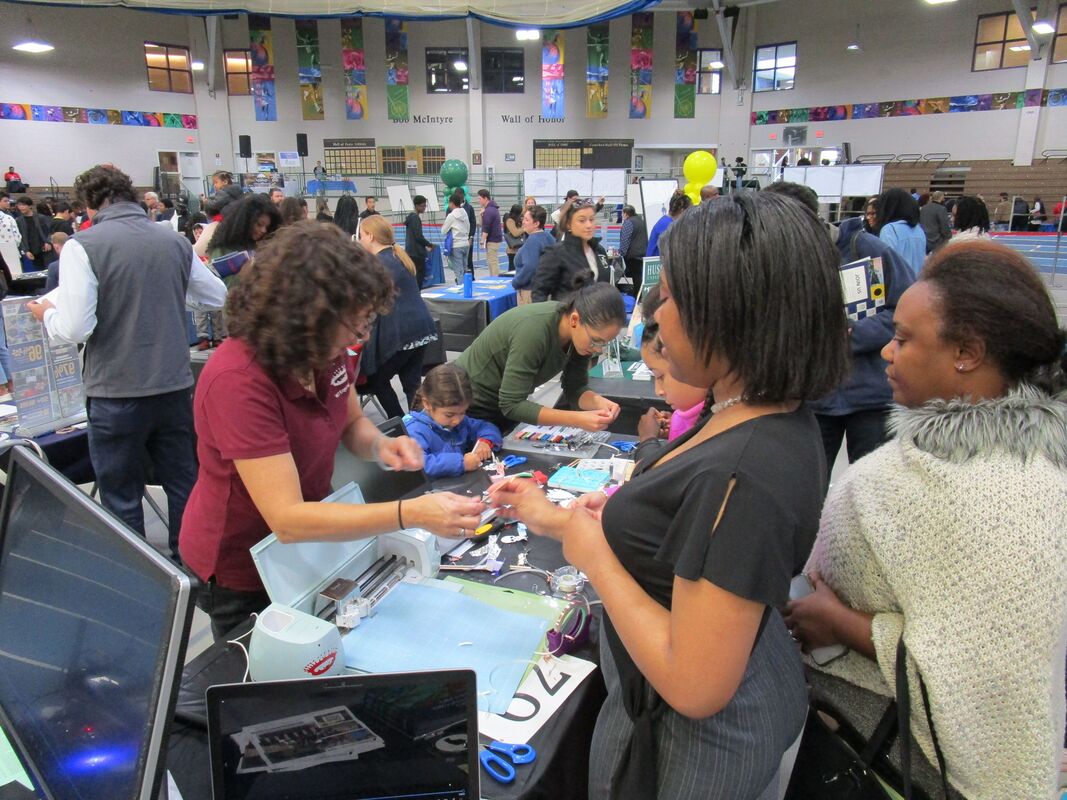 photo of a busy event with people checking out projects at a series of tables
