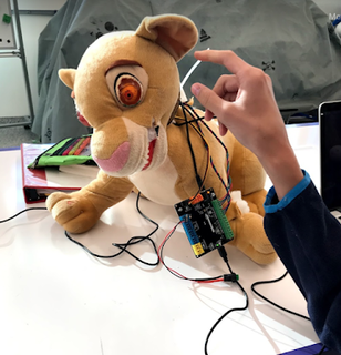 photo of a maker project: a stuffed lion toy with wires and a battery pack coming out