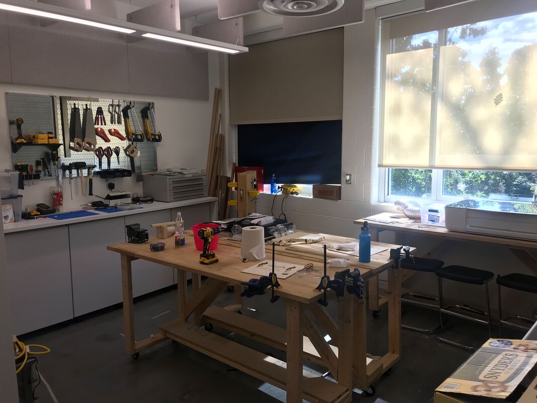 Photo of a maker space with tools hanging neatly on the wall and a big work table
