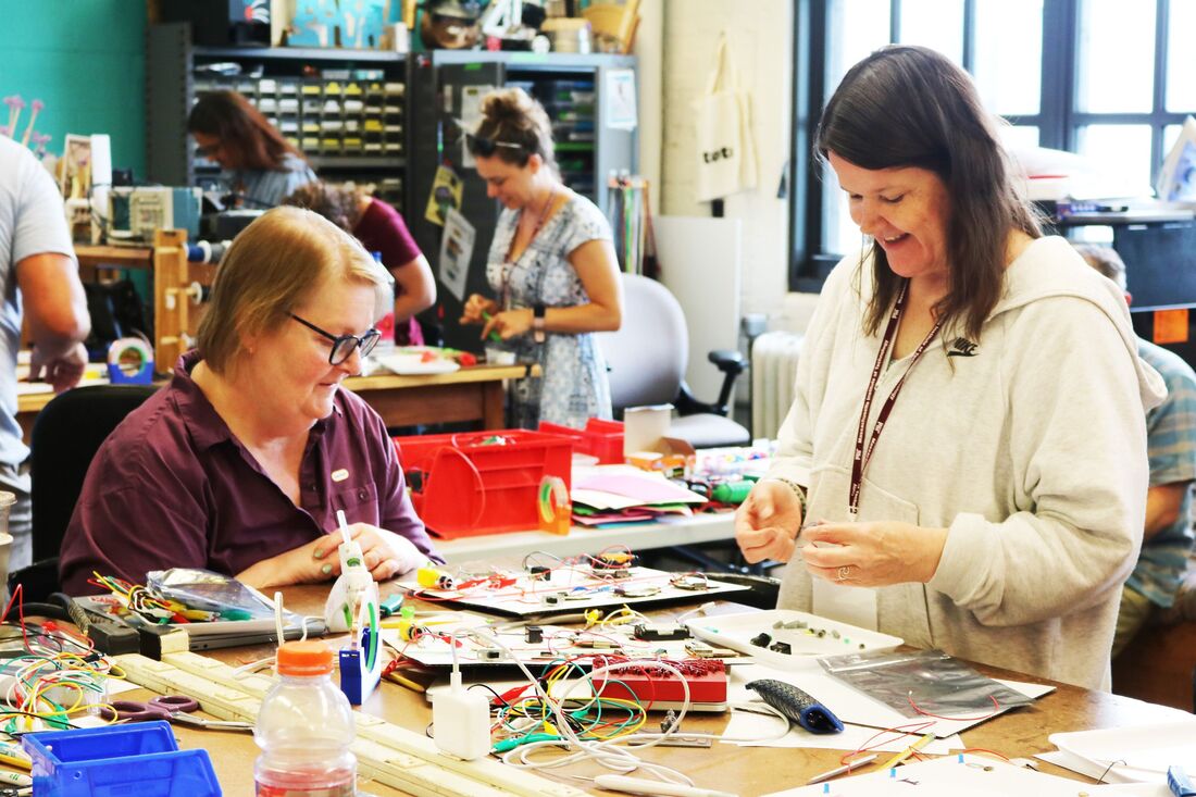 Photo of teachers playing a xylophone on a cluttered workbench