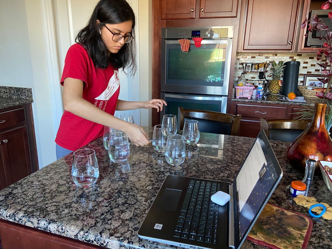 Student playing music on glassware in a kitchen