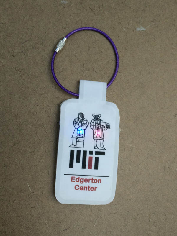 a keychain with an MIT logo, with 2 lit LEDs