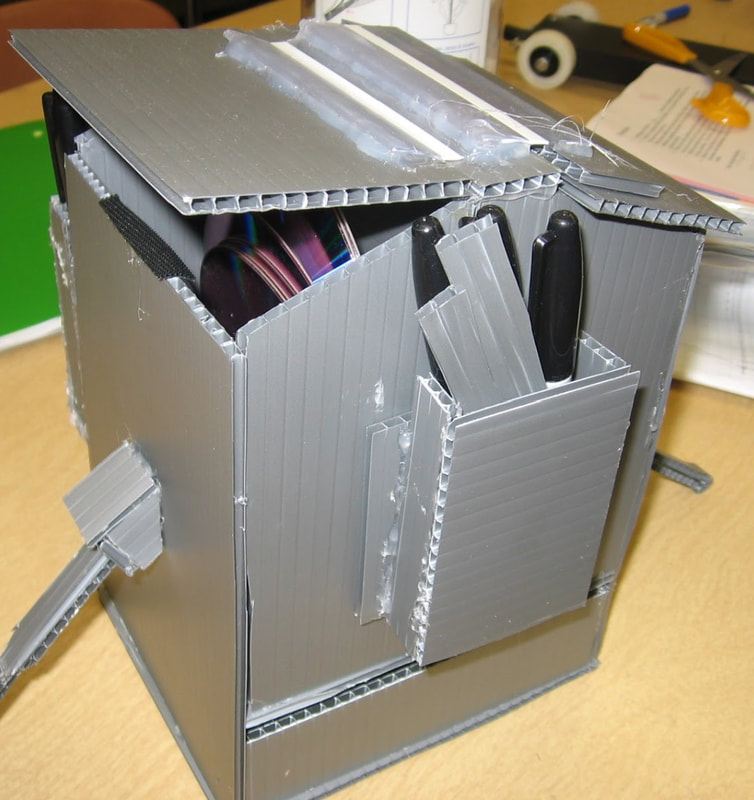 an office-supply organizing caddy made from corrugated plastic, holding sheets of craft material and markers