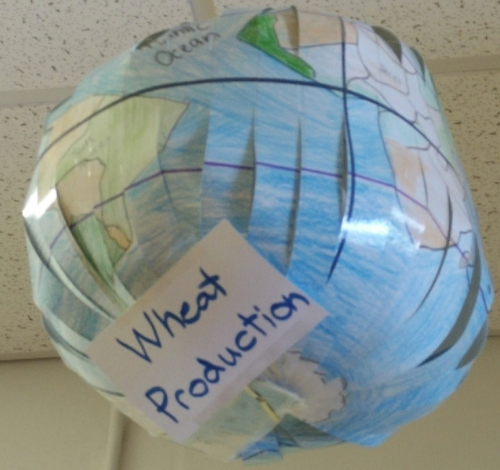 a paper globe marked with a sign reading "wheat production" and maps marked to show major wheat producing regions